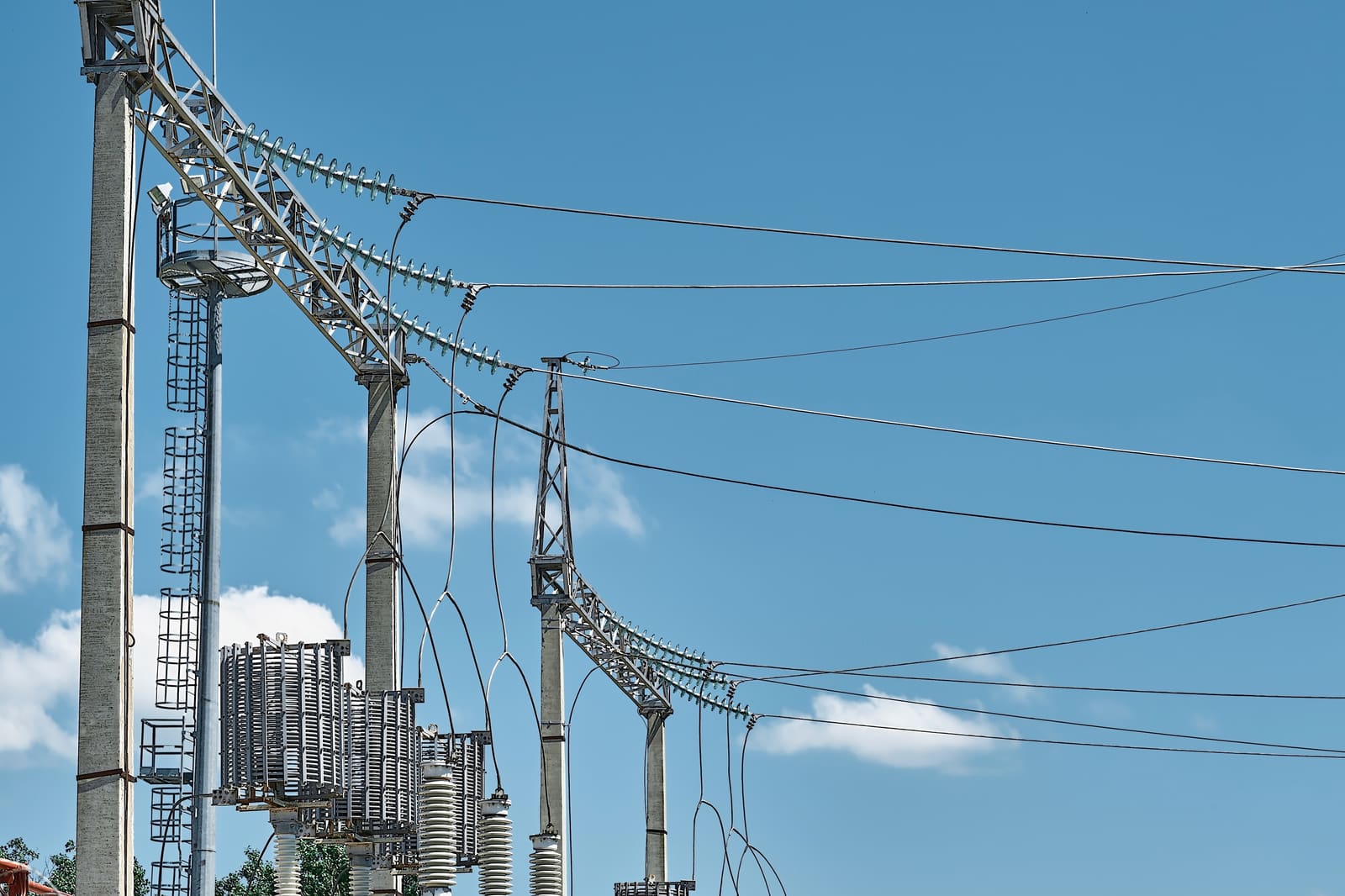 High-voltage substation gantry and transmission conductors under a clear sky