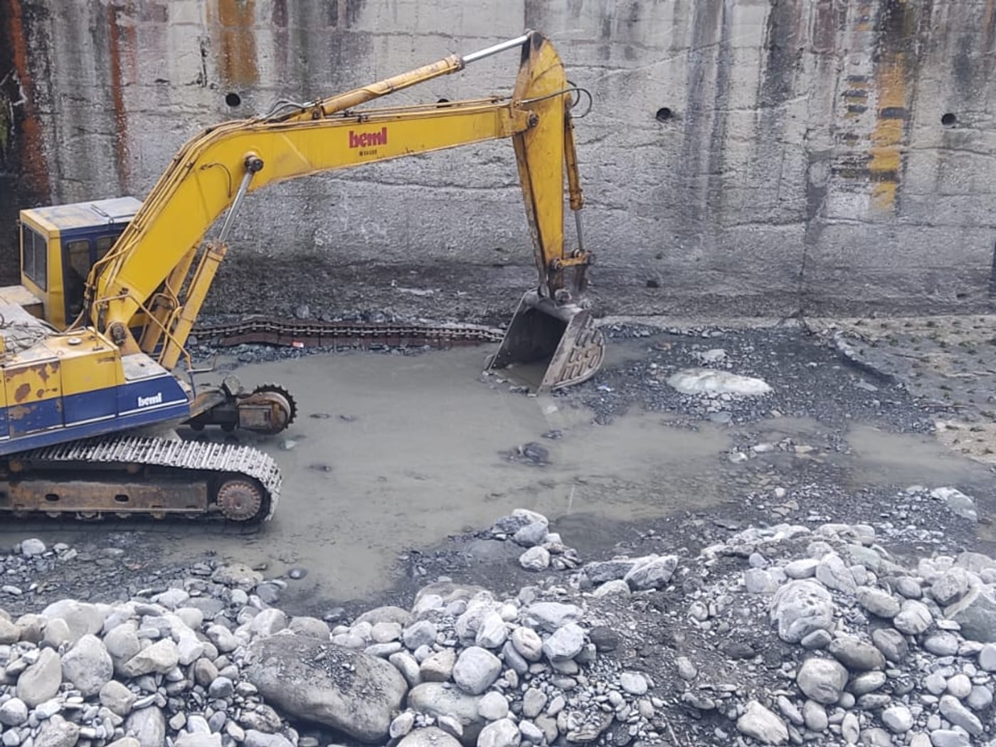 Excavator desilting the drained, silt-choked trench weir intake bay at Bhaledh